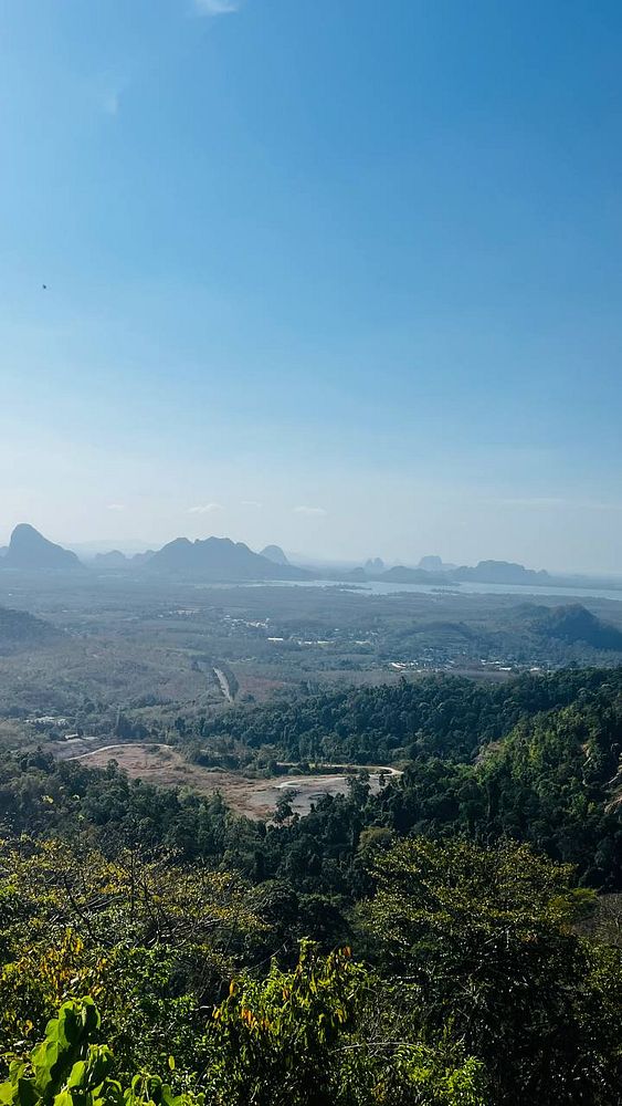 View from the Wang Kelian viewpoint showing a wooden platform extending over lush green hills under a partly cloudy sky.