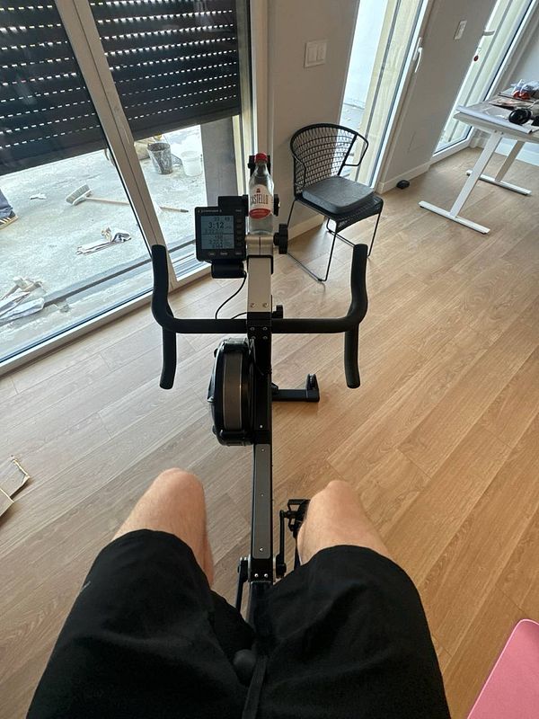 A person is seated on a rowing machine in a home gym setting.