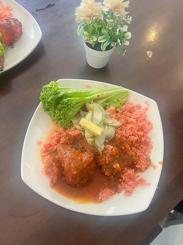A plate of nasi tomato with ayam masak merah and fresh vegetables.