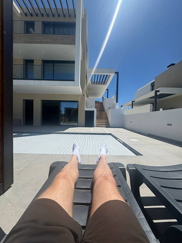 A person is relaxing by a poolside in a modern outdoor setting.