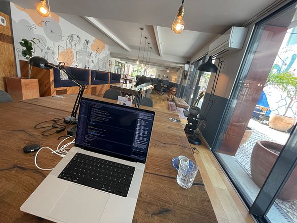 A workspace in a coworking area featuring a laptop, modern decor, and a view of the outdoors.