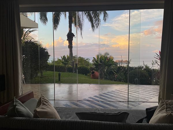 Luxurious hotel room with large windows overlooking the Pacific Ocean at sunrise.