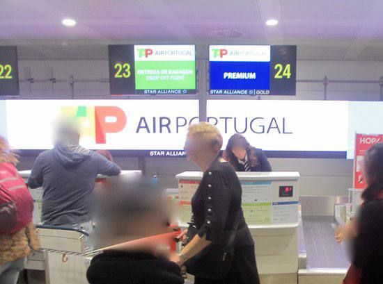Passengers are checking in at the TAP Air Portugal counter at Amsterdam Schiphol Airport.