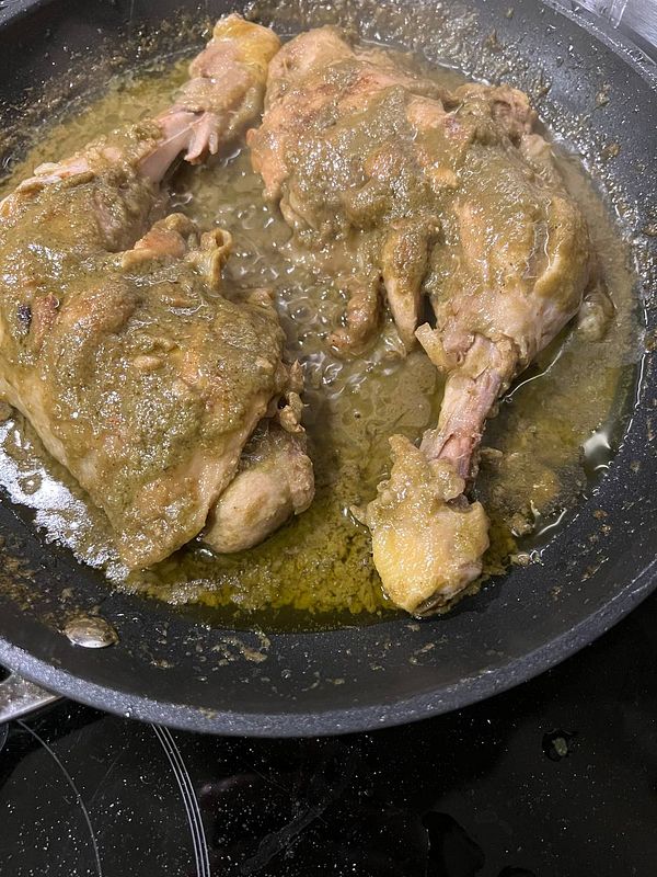 The image features chicken pieces cooking in a green sauce in a frying pan.