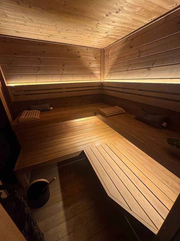 A cozy wooden sauna interior with benches and soft lighting.