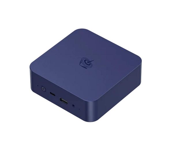 Front view of a compact mini PC kit including a small black device, stand, and smartphone for size comparison on a wooden surface.