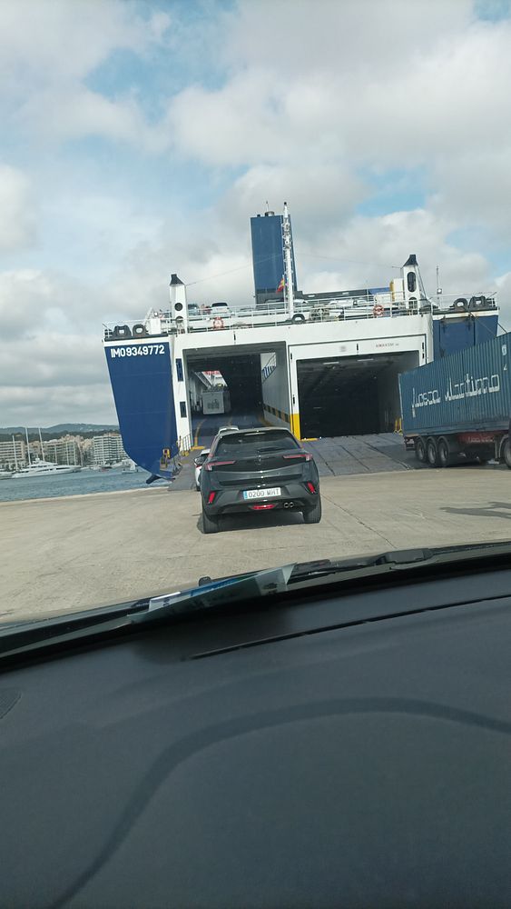 A ferry deck view of the sea under a cloudy sky with open water ahead.