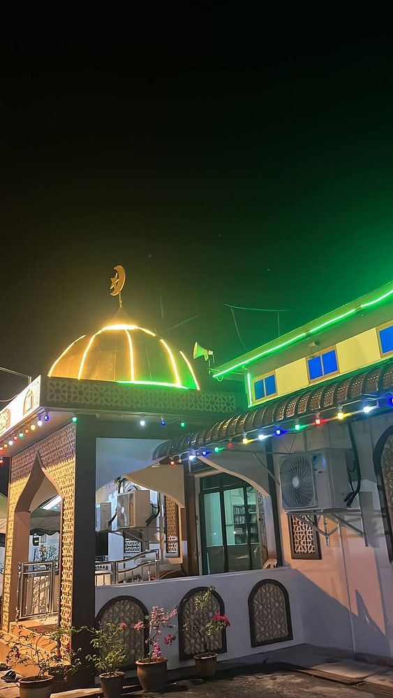 A beautifully illuminated mosque at night, adorned with colorful lights for Eid prayers.