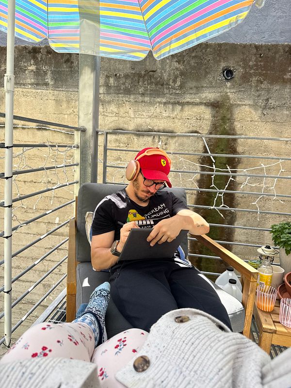 A cozy outdoor patio setup with a wicker chair and table, featuring a journal and eyeglasses on the table, ideal for reading.