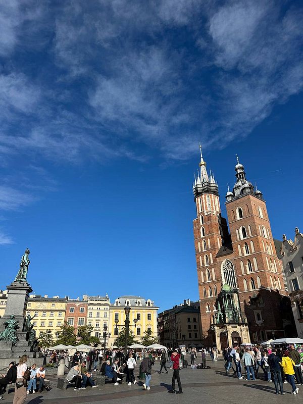 A vibrant city square bustling with people under a clear blue sky.