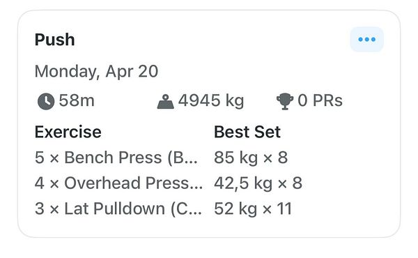 Two men in a gym lifting barbells in front of full-length mirrors.
