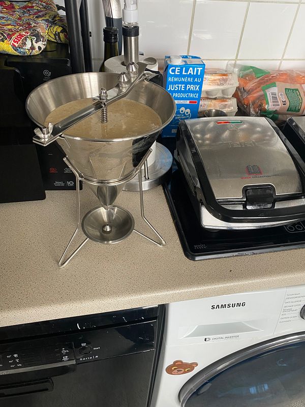 A stack of golden-brown pancakes topped with butter on a white plate, accompanied by maple syrup in a clear glass container and a fork.