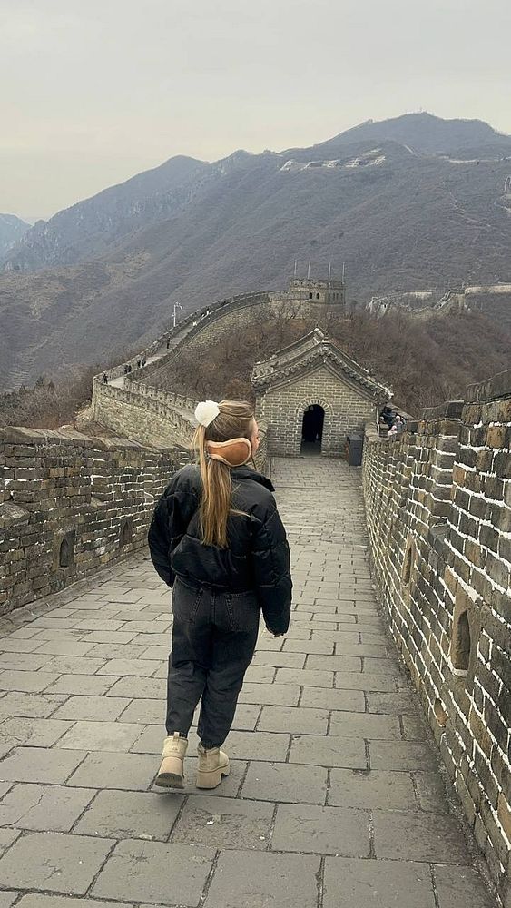 A child walks along the Great Wall of China, surrounded by mountainous terrain.