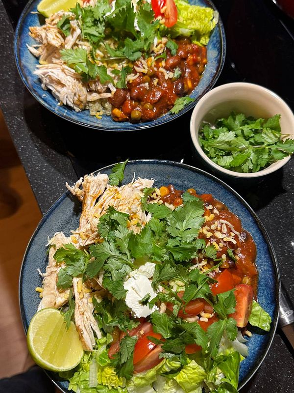 Colorful vegetarian burrito bowls arranged on a wooden table with various fresh ingredients and side dishes.