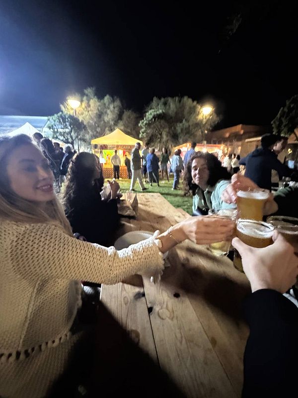 A lively gathering at the Beerceira festival with friends toasting with beers.