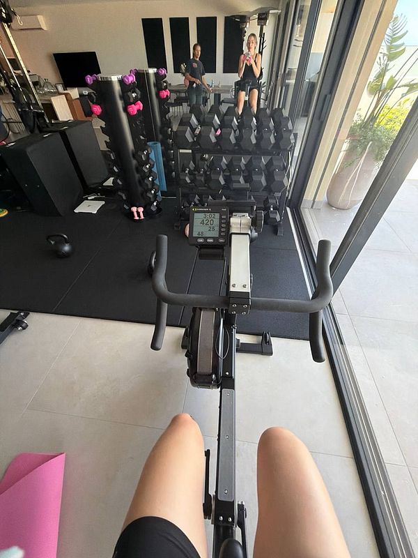 Photo of a gym workout setup including gym flooring, a kettlebell, dumbbells, and a jump rope.