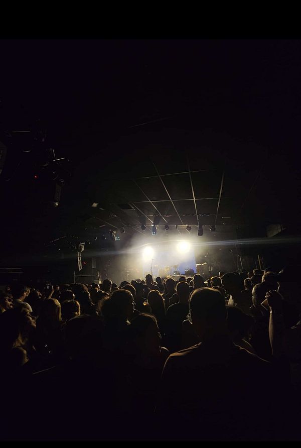 Crowded concert venue with stage lights shining brightly toward the audience.