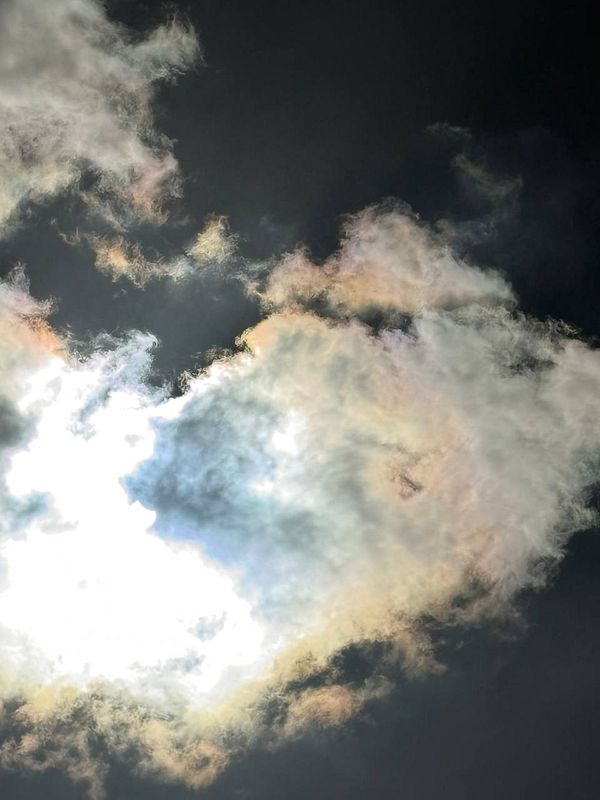 A dramatic sky featuring clouds illuminated by sunlight with colorful edges.