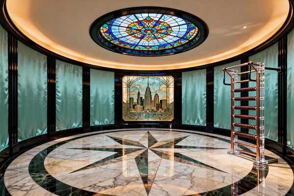 A circular home gym showcases a glossy white marble floor with a large emerald compass inlay, framed by black lacquered pilasters and aqua satin wall panels. Overhead, a colorful stained-glass oculus and warm cove lighting illuminate a backlit Art Deco cityscape panel, while a freestanding acrylic dumbbell rack with polished copper fittings and brown leather weights stands to the right, reflecting across the marble and expressing a vintage glam aesthetic.