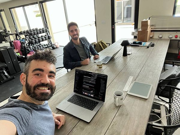 Two men are working together at a large wooden table in a modern workspace.