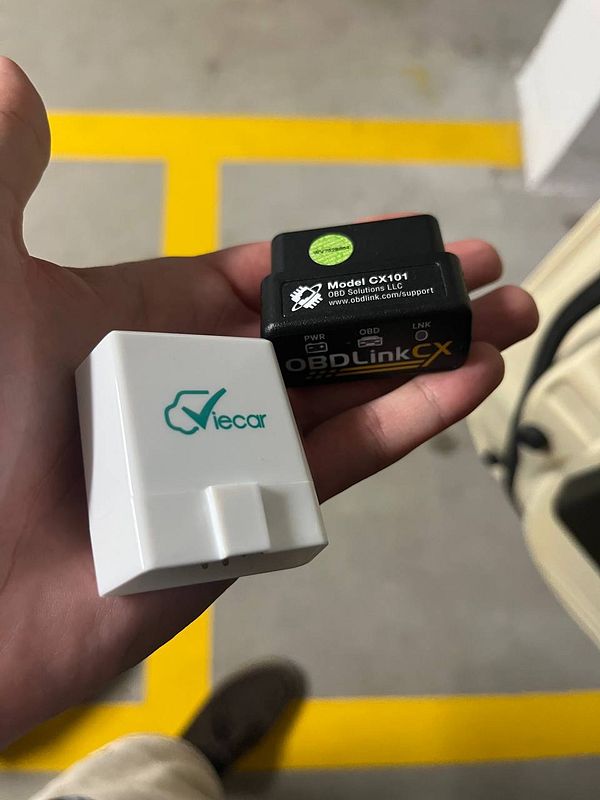 Wiring setup of a vehicle OBD-II port connected with black and blue wires fastened by a cable tie inside the engine bay.