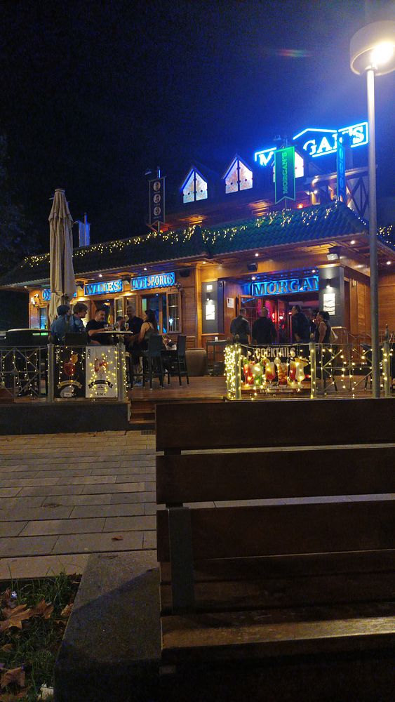 A lively Irish pub illuminated at night, featuring outdoor seating and festive decorations.