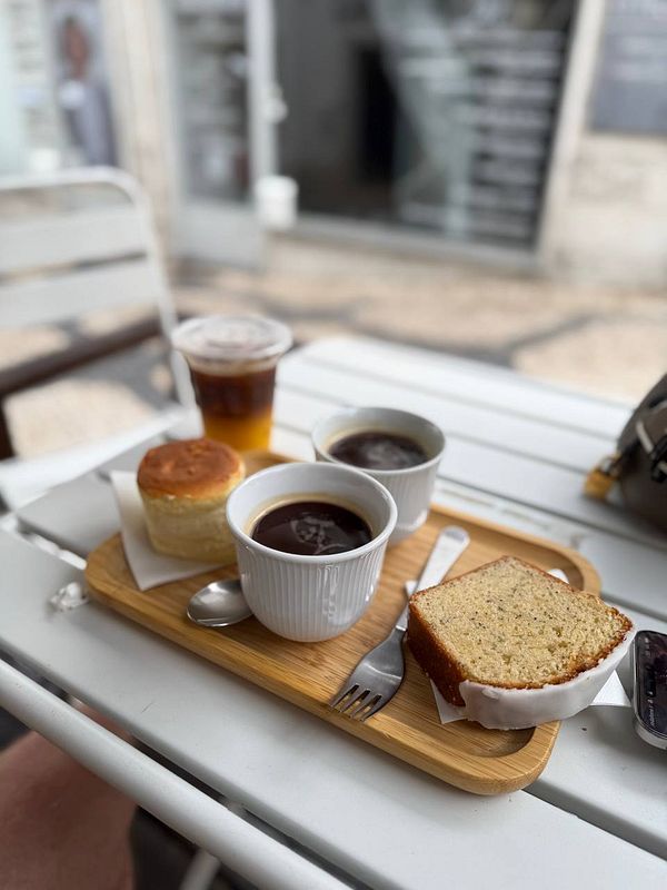 A cozy coffee setup featuring a variety of beverages and pastries on a wooden tray.