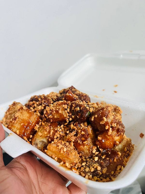 A hand holds a container filled with Rojak Cina, a popular Singaporean dish.