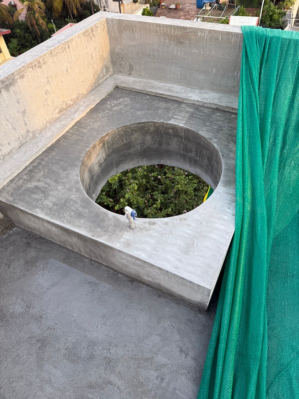 A rooftop area features a circular opening surrounded by concrete and a green netting.