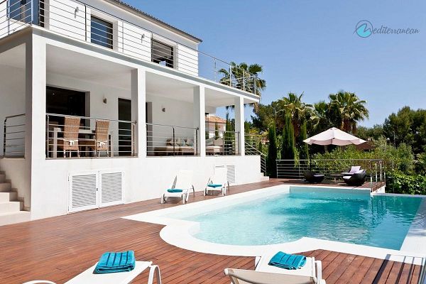 A modern villa with a swimming pool and outdoor seating area surrounded by lush greenery.