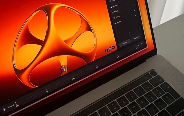 A close-up view of a MacBook Pro displaying a vibrant 3D design interface.