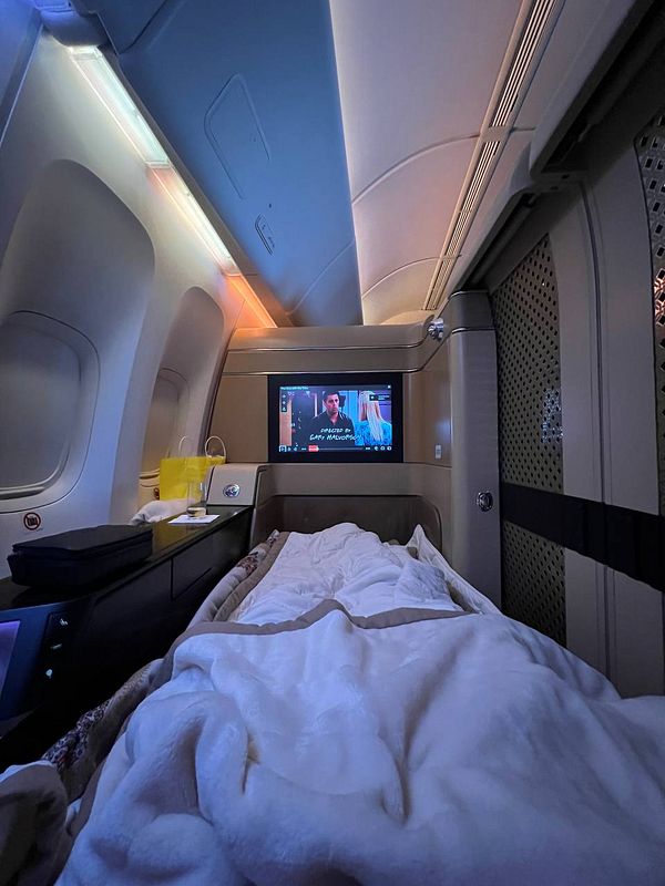 A luxurious airplane cabin featuring a comfortable bed and an entertainment screen.