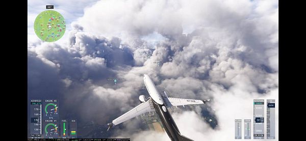An aircraft is flying through a dense cloud layer above a landscape.