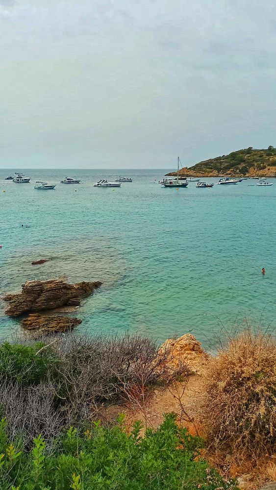 A serene beach scene featuring boats on calm waters under a cloudy sky.