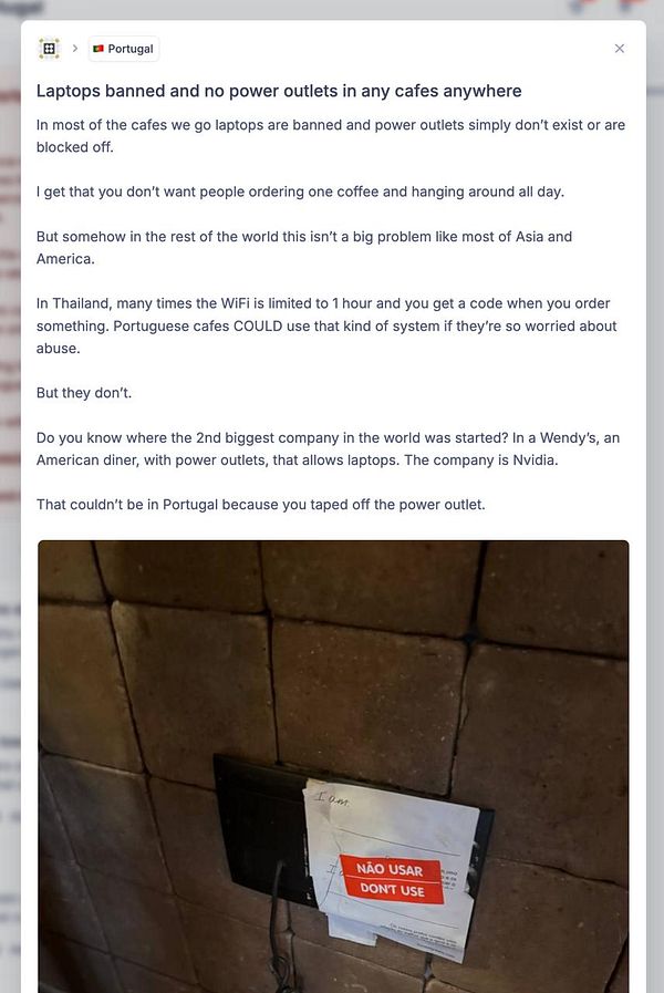 A power outlet is taped off with a warning sign in a cafe setting.