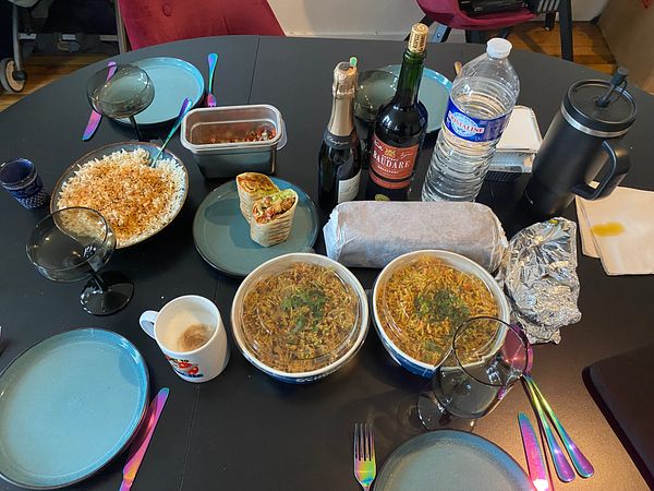 A dining table is set with a variety of food and drinks, indicating a family meal.