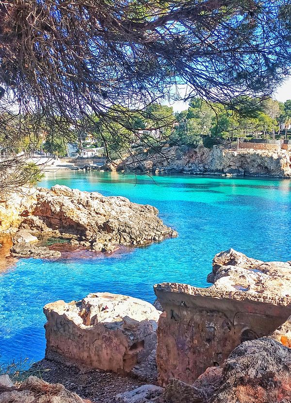 A scenic view of a tranquil blue bay surrounded by rocky formations and greenery.