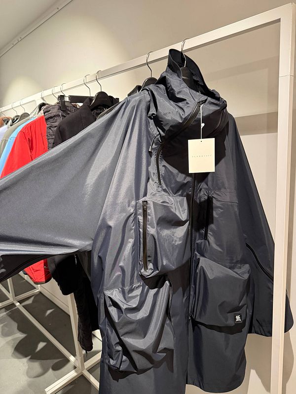 A fashion runway scene at Paris Fashion Week featuring a model walking down the catwalk with a large audience on both sides.