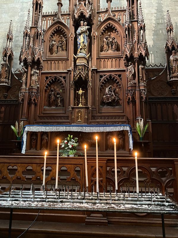 Interior of a modern church sanctuary featuring wooden pews, a large cross, and a stained glass window with vibrant colors.