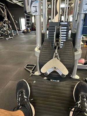 A close-up view of a gym machine with a focus on the footplate and weights.