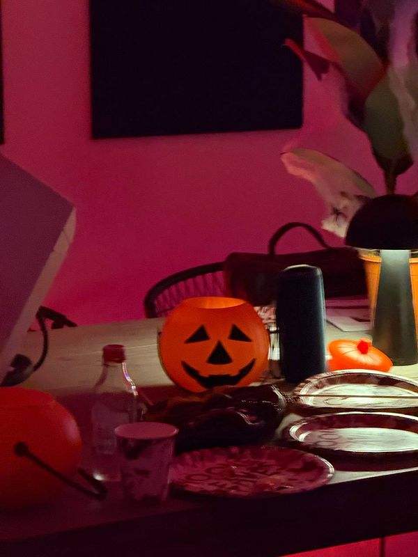 A festive Halloween-themed table setting with decorations and food items.