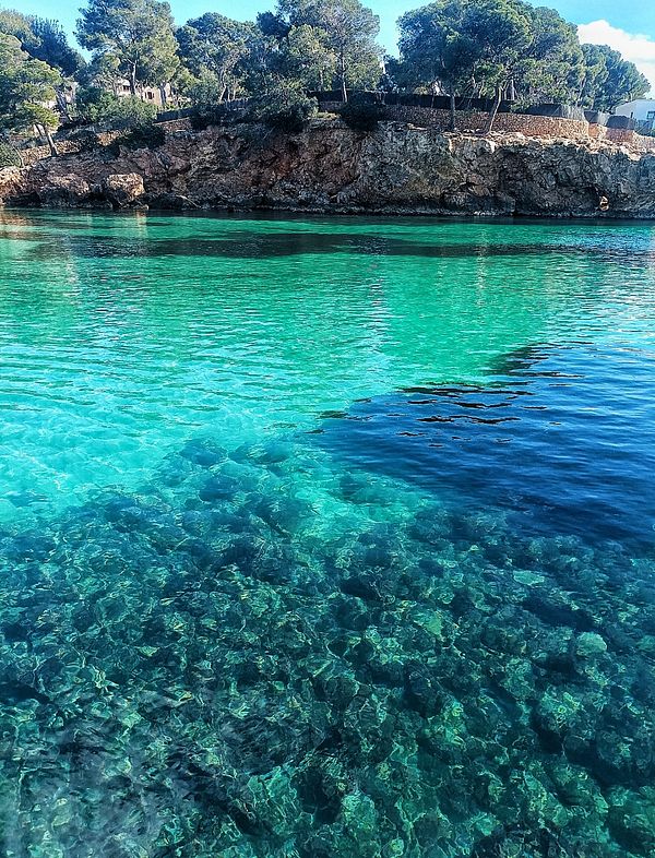 A serene coastal scene featuring clear turquoise waters and rocky shores.
