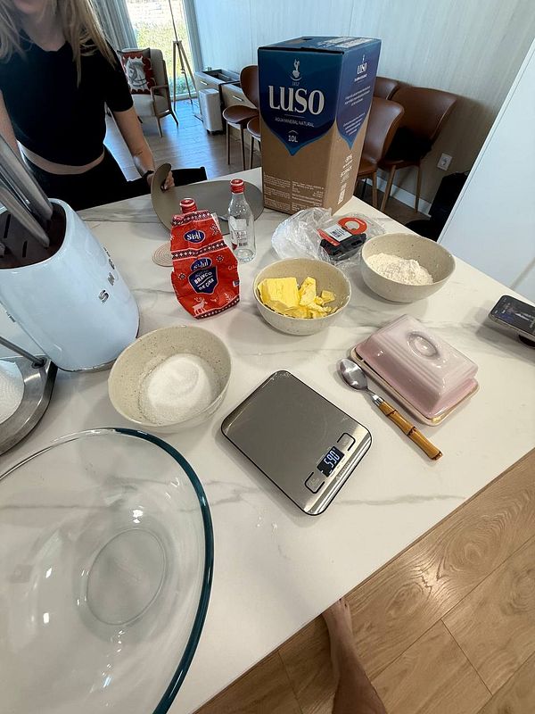 A kitchen countertop is set up with various ingredients and tools for making butter cake with blueberries.