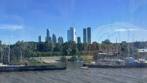 A view of the Buenos Aires skyline from a ferry, showcasing modern skyscrapers and a marina.
