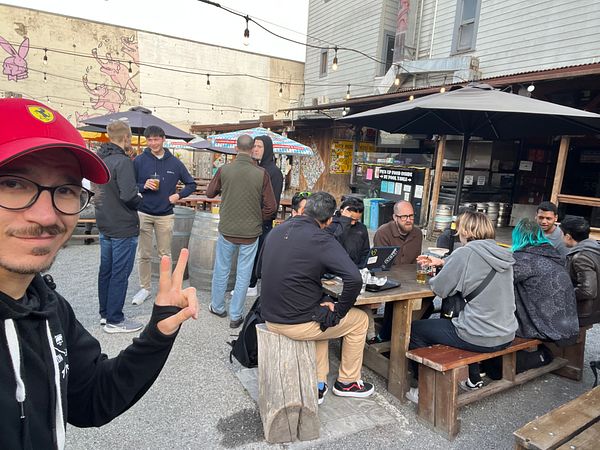 A group of people gathers outdoors at a meetup, enjoying drinks and conversation.