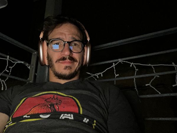 Top-down view of a creative workspace with people collaborating around a wooden table filled with stationery and electronic devices.