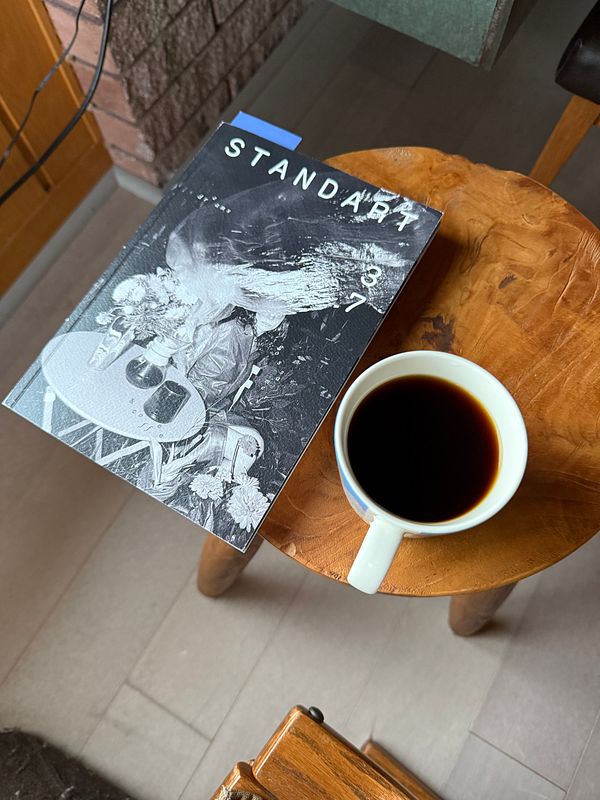 A cozy Sunday morning scene featuring a cup of coffee and a magazine on a wooden table.