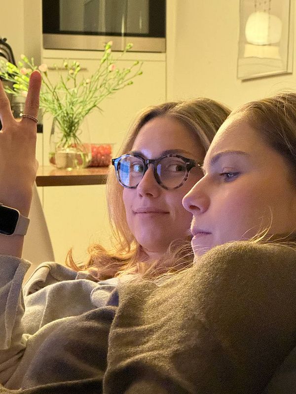 Two young women are sitting closely together, engaged in a moment of leisure.