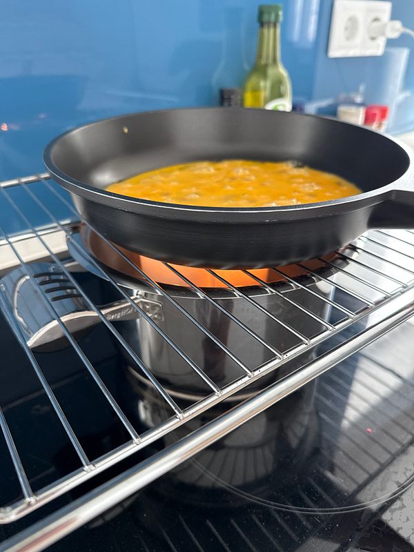 A frying pan with eggs is placed on a stovetop setup designed for cooking without electricity.