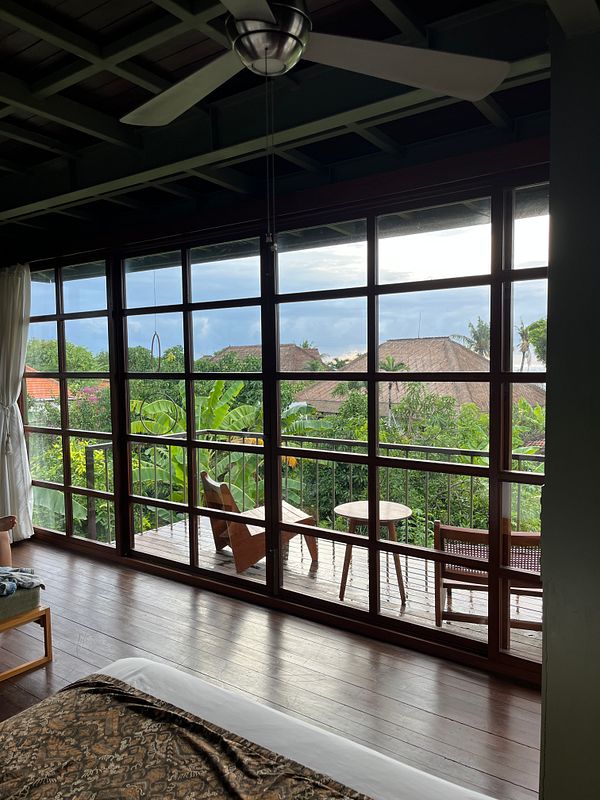 A cozy room with large windows overlooking a lush outdoor area.